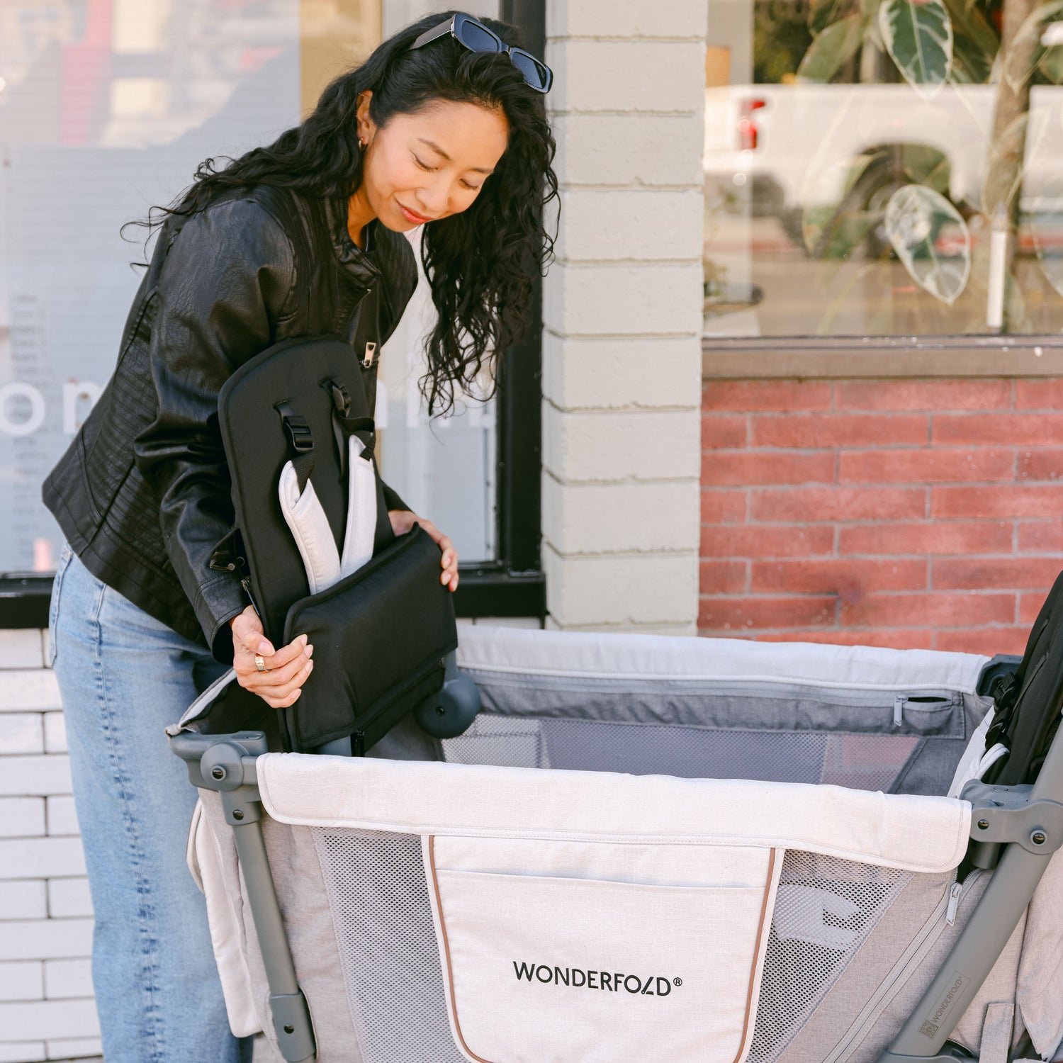 A woman adjusting the removeable, foldable seat of a WonderFold L2 stroller wagon, demonstrating its versatile and spacious design