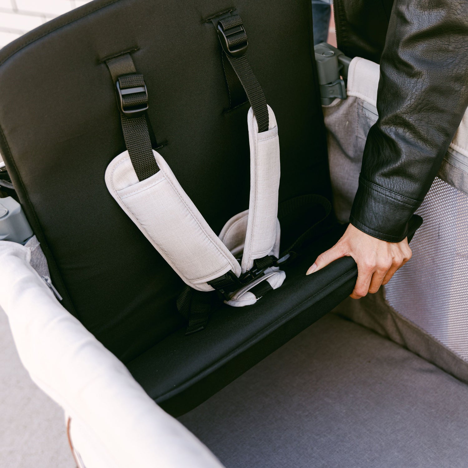 A close-up of a hand lifting the seat inside the WonderFold L2 stroller wagon, showcasing its adjustable and secure design.