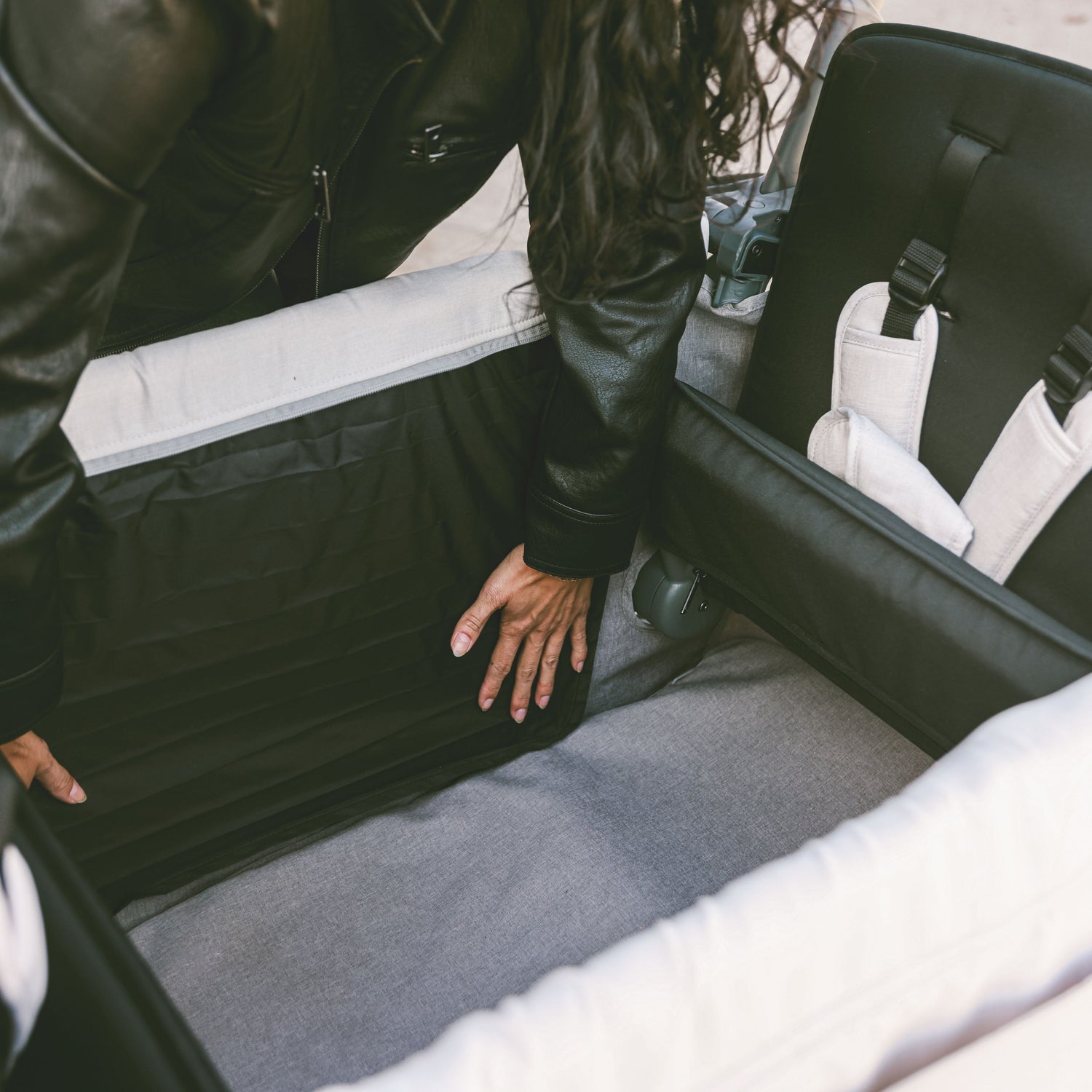 A woman adjusting the wind and privacy shade inside the WonderFold L2 stroller wagon, demonstrating its spacious and customizable interior.