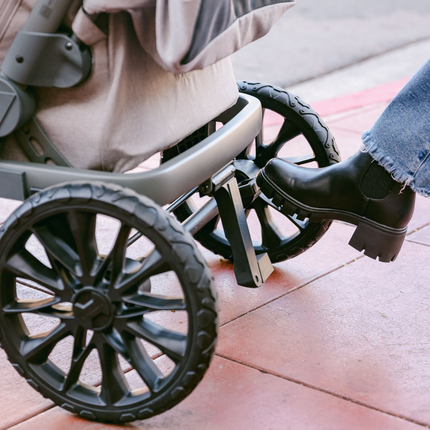 A foot pressing the brake pedal on the WonderFold L2 stroller wagon, highlighting its secure and easy-to-use braking system