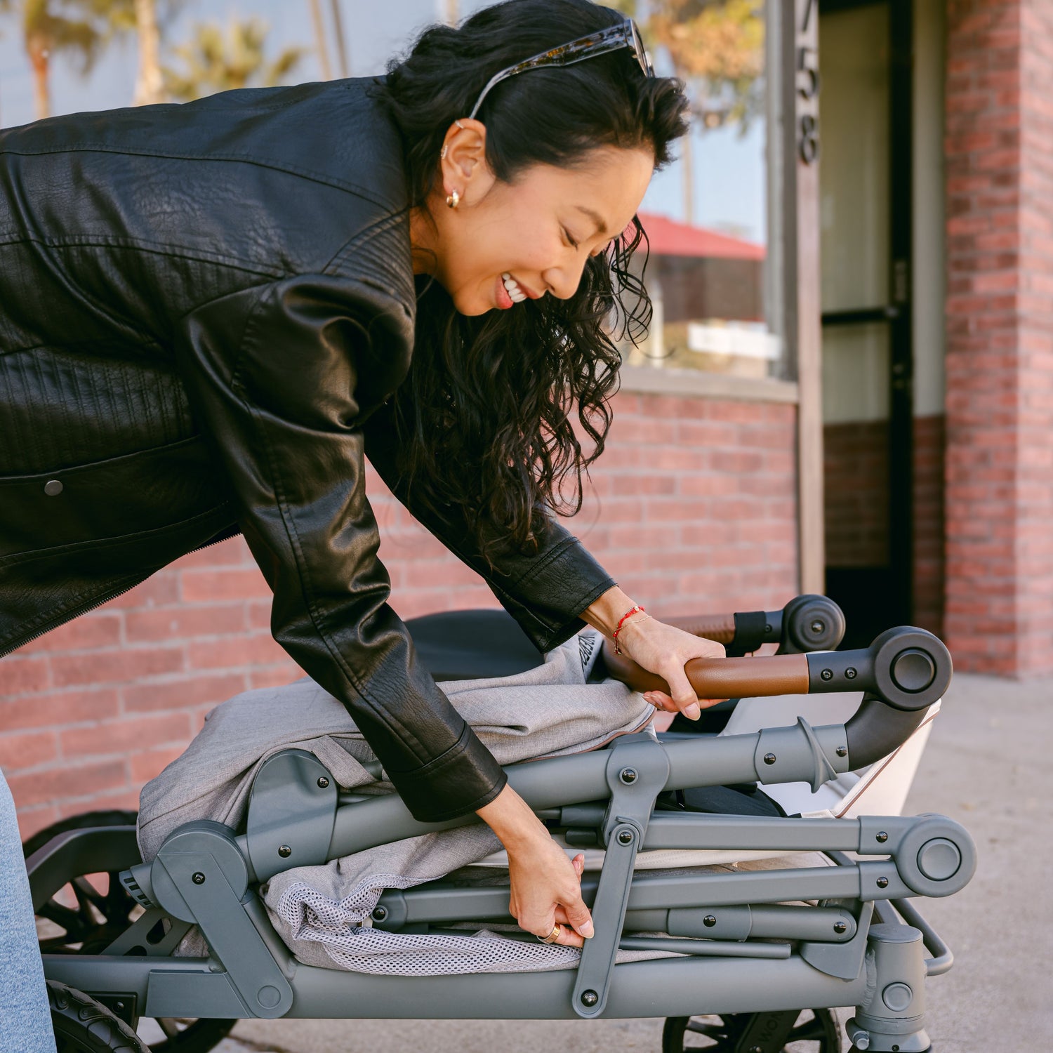 A woman folding down the WonderFold L2 stroller wagon, showcasing its compact and portable design.