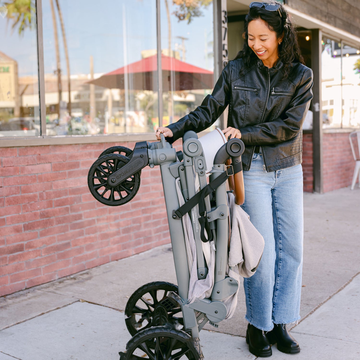 A woman folding the WonderFold L2 stroller wagon, demonstrating its compact and easy-to-carry design.