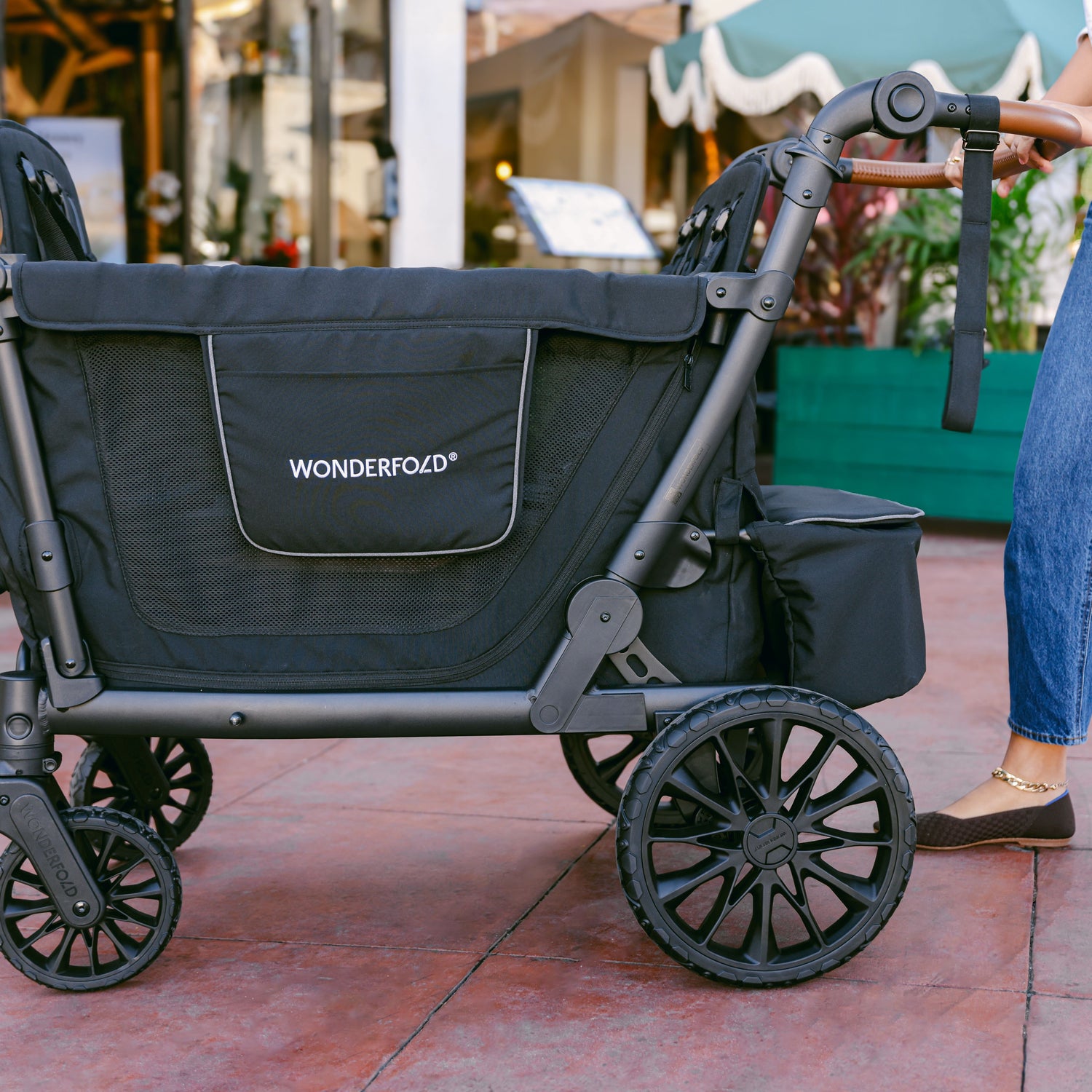 Side view of the WonderFold L4 stroller wagon, showcasing its sleek black design, mesh panels, and storage pockets.