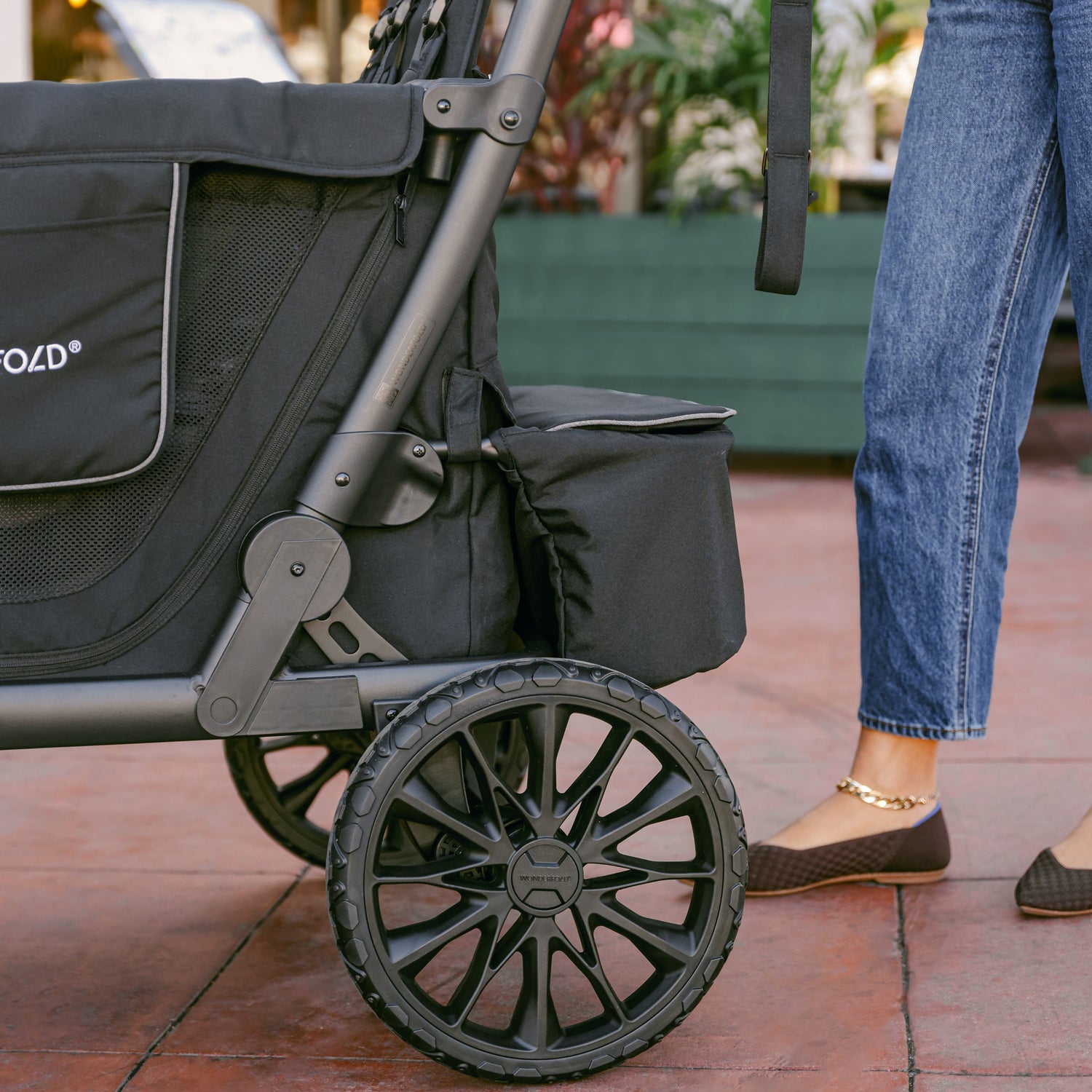 Close-up of the XL All-Terrain Wheel and rear storage fabric on the WonderFold L4 stroller wagon, highlighting its sturdy build.