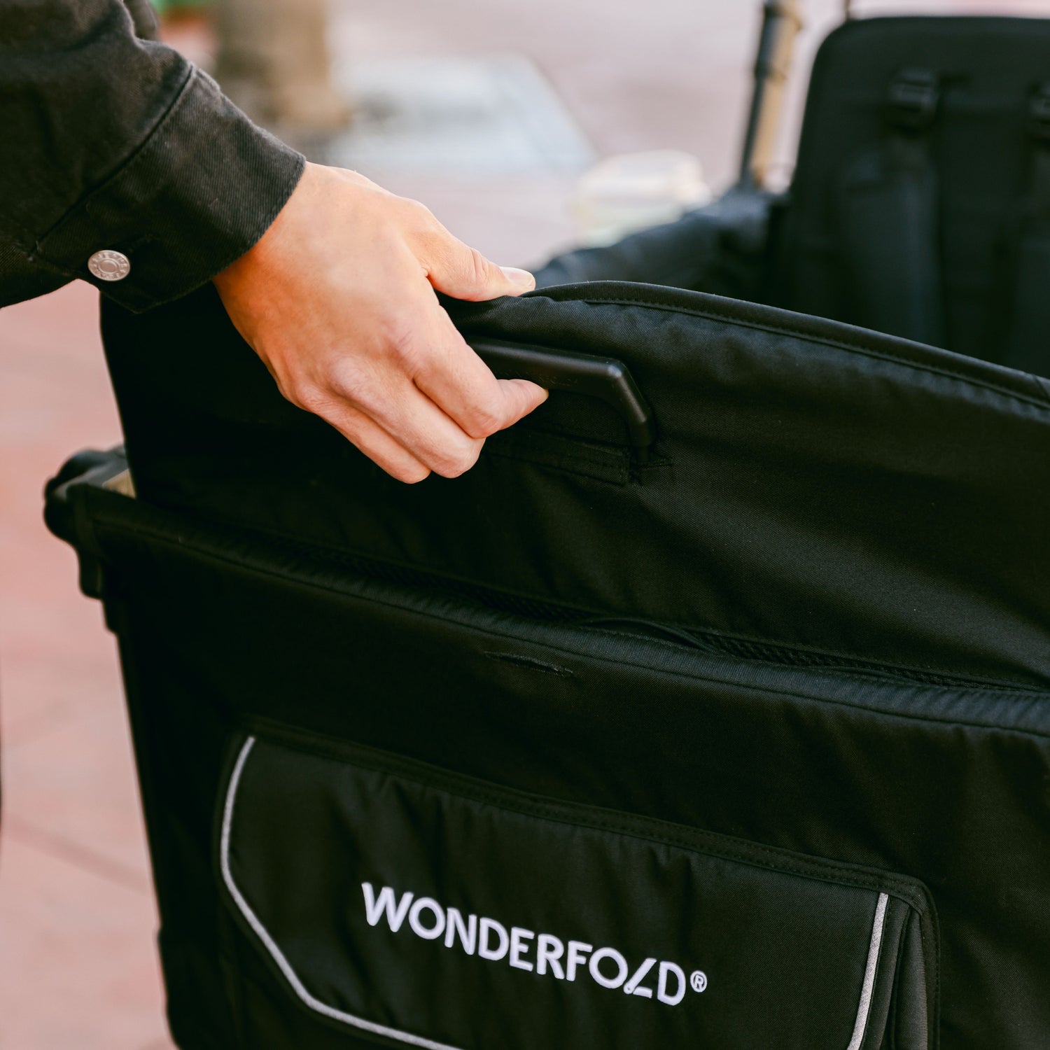 A close-up of a person lifting the removable seats of the WonderFold L4 stroller wagon.