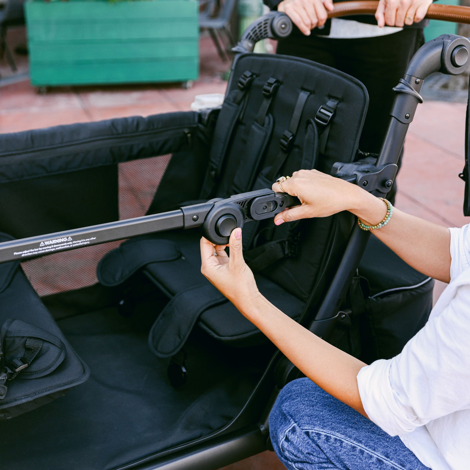 A woman adjusting the side door open system of the WonderFold L4 stroller wagon, demonstrating its adjustable design.