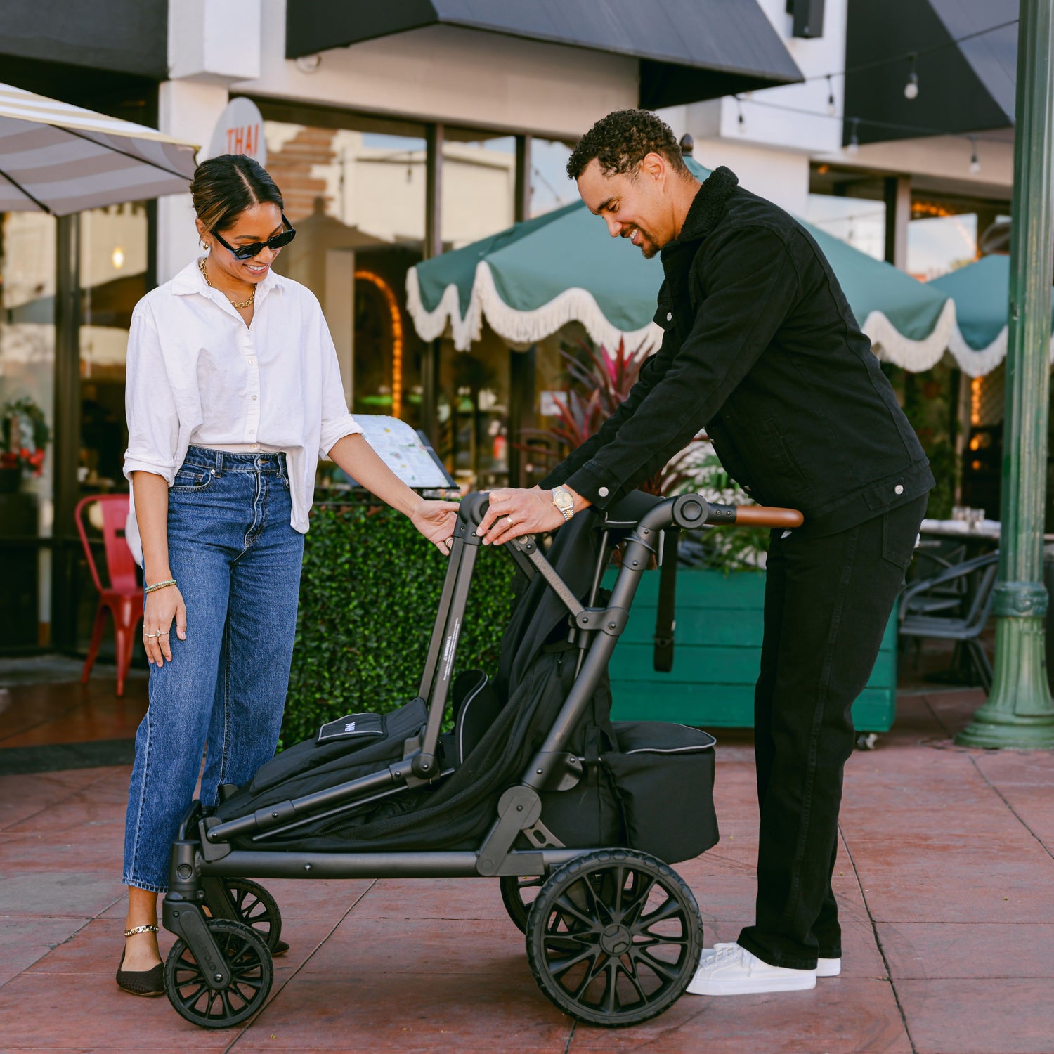 A couple folding the WonderFold L4 stroller wagon, demonstrating its collapsible and travel-friendly design.