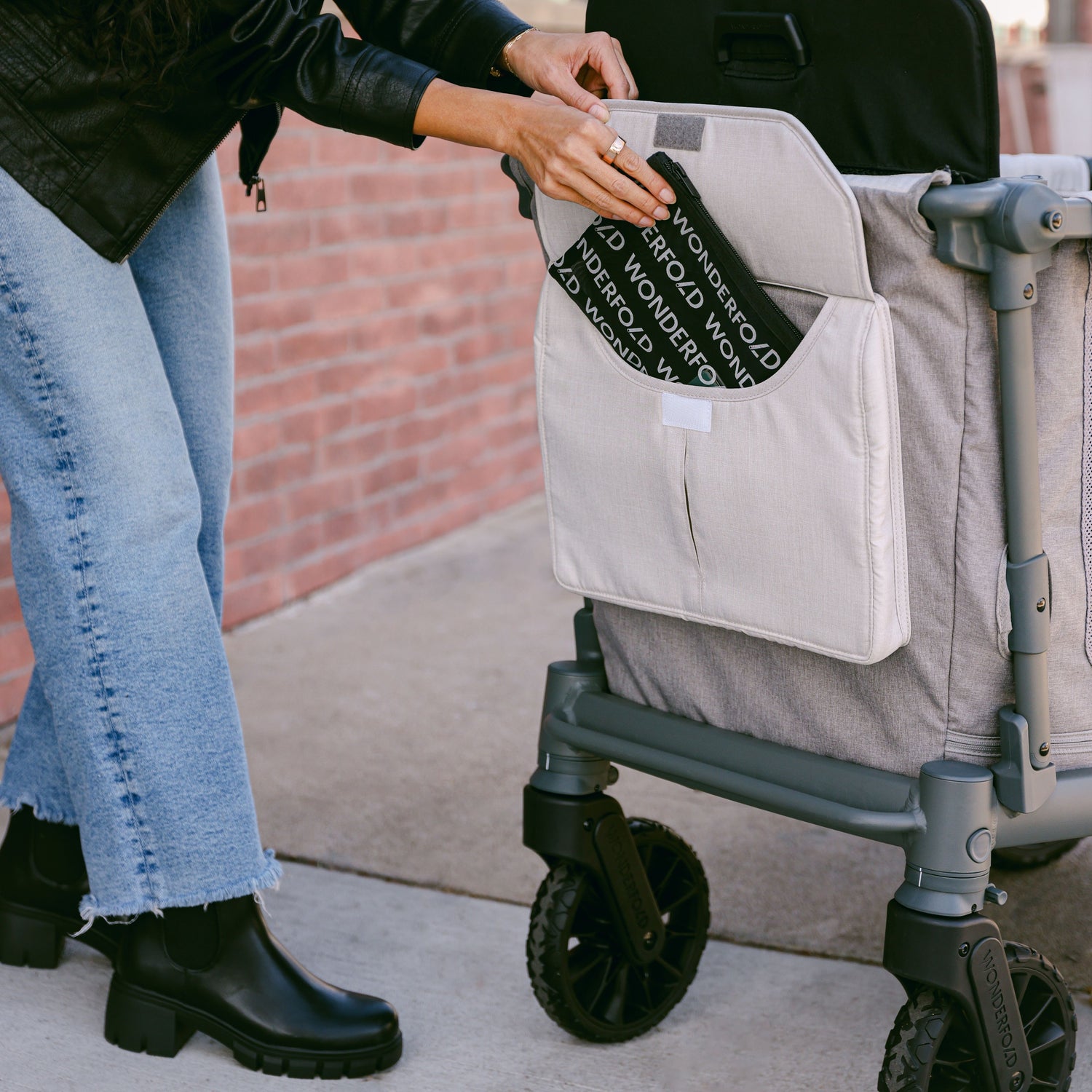 A woman using the front storage pocket of the WonderFold L2 stroller wagon.