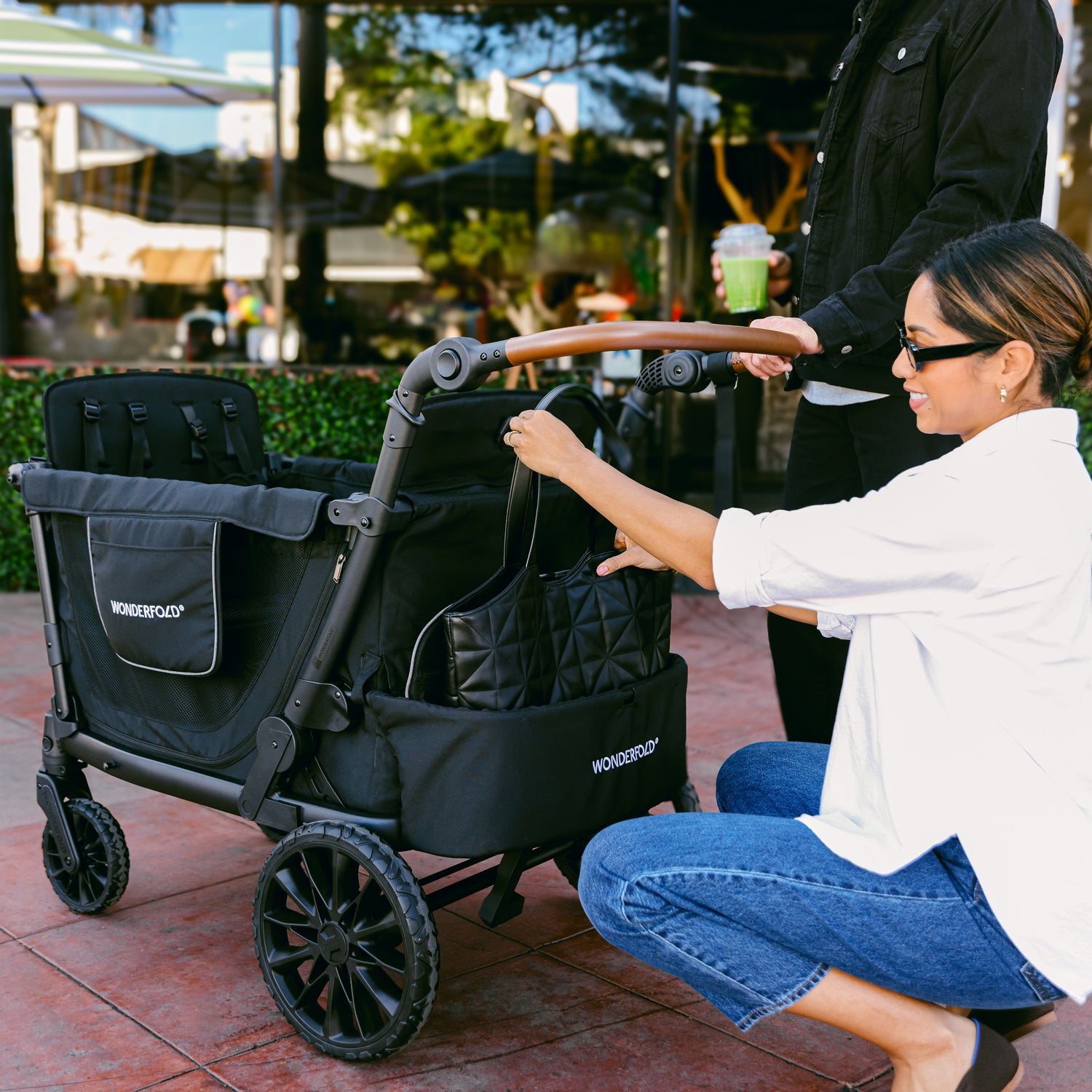 A woman placing her purse inside the rear storage fabric of the WonderFold L4 stroller wagon.