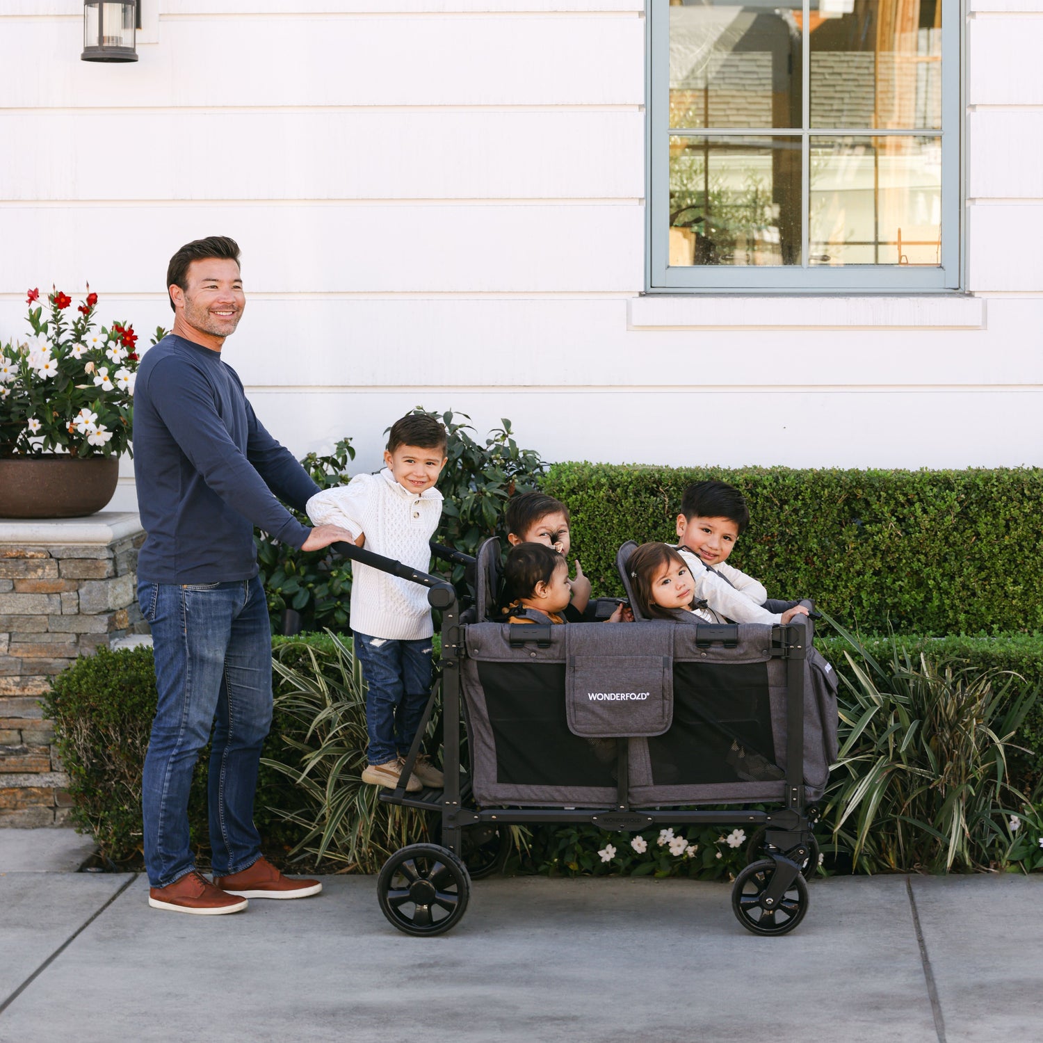 Family using the WonderFold stroller wagon with the Buddy Board accessory for a comfortable outing