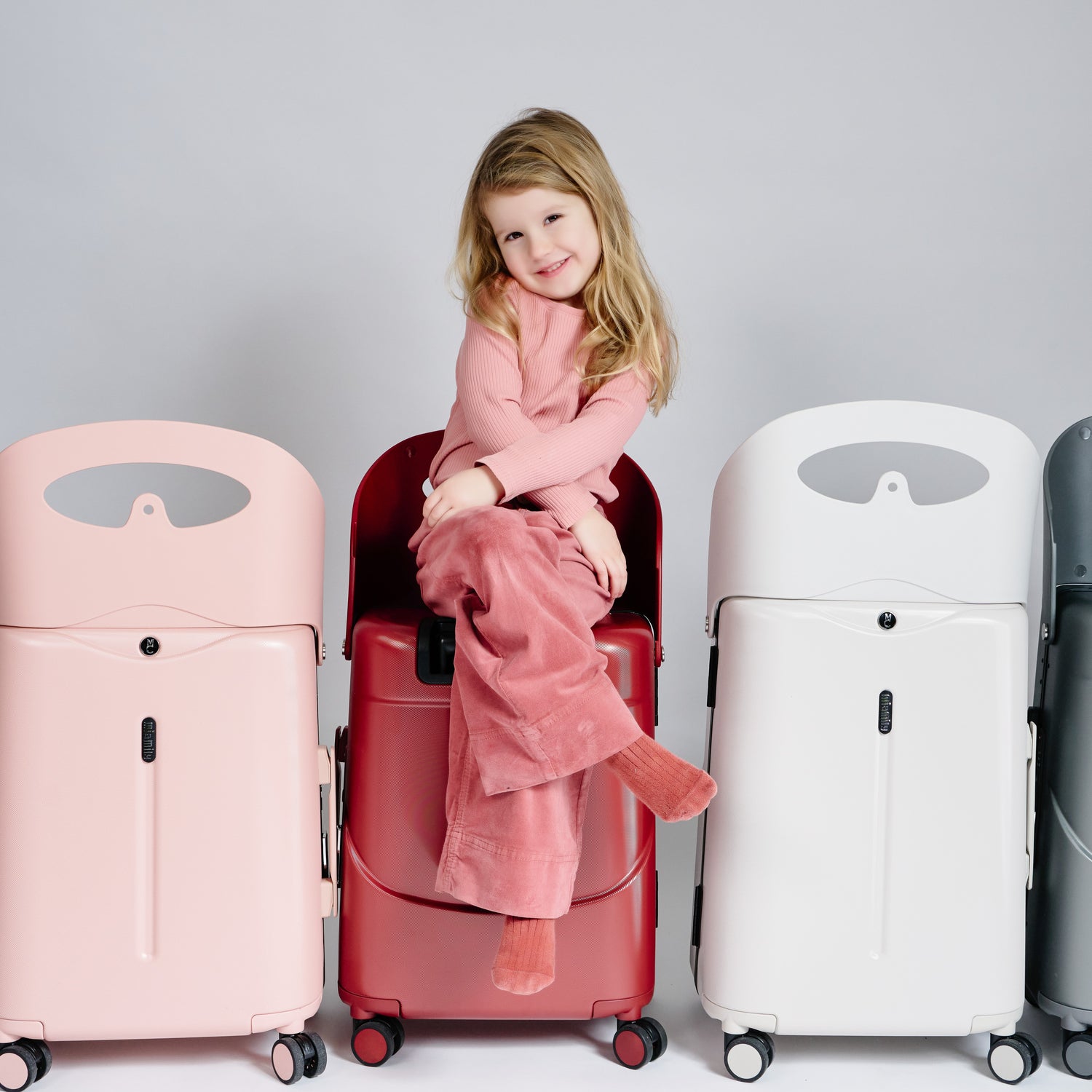 Little girl sits on a carry-on luggage