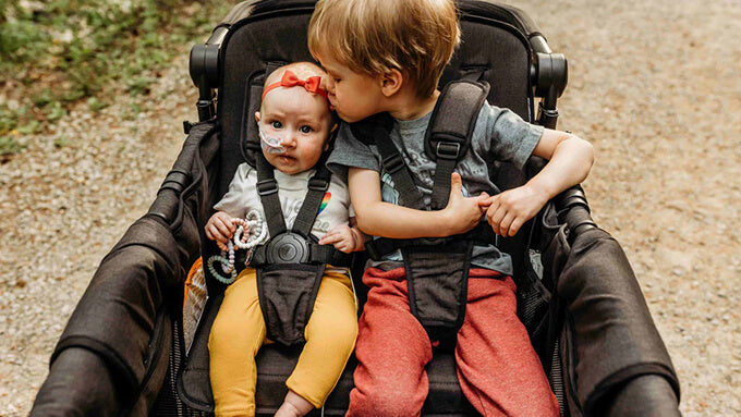 Two children sitting together in a WonderFold stroller wagon