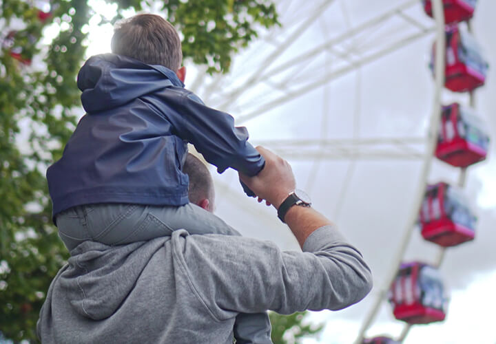 Father carrying his child on his shoulders at a fair