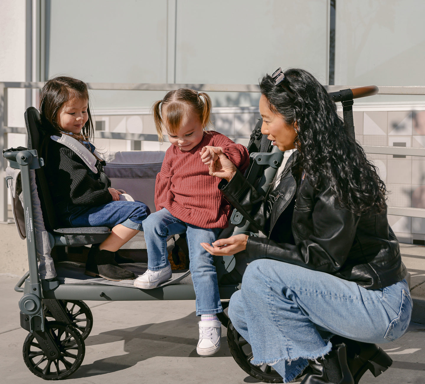 Parent with two children seated in a Wonderfold L Series stroller wagon