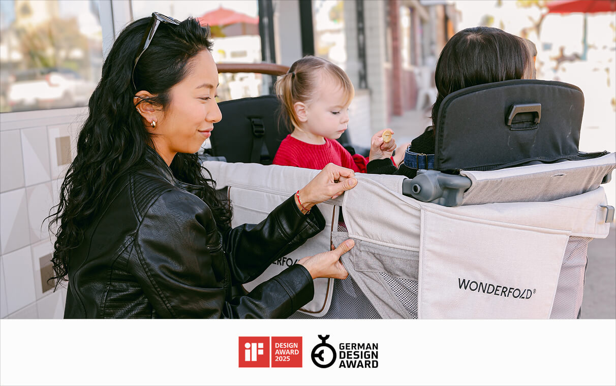 Parent buckling a child into the L Series wagon, with the iF Design Award 2025 and German Design Award logos
