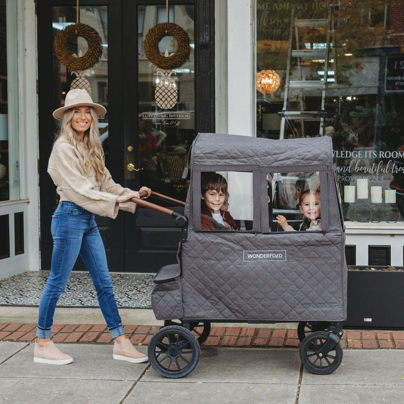 mom pushing toddler wagon with winter cover