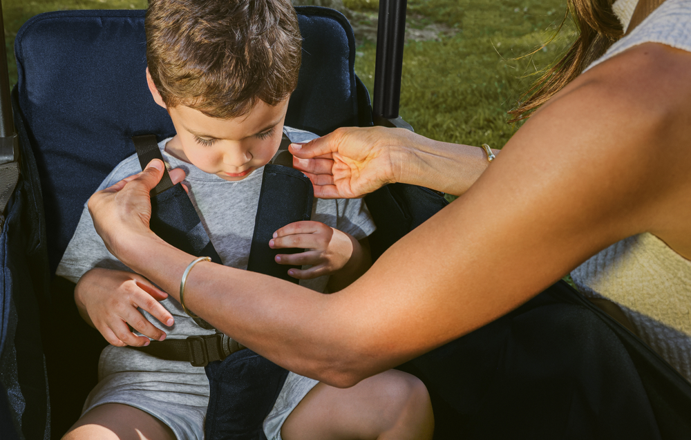 Mom adjusting the XR stroller wagon's harness for her child.