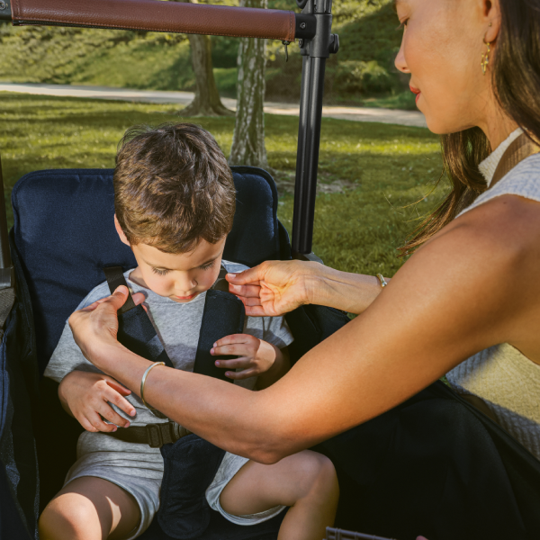 Mom adjusting the XR stroller wagon's harness for her child.