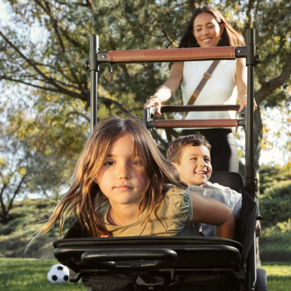 A mom pushing her children in the XR stroller wagon outside.